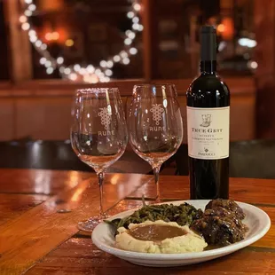 a plate of mashed potatoes, gravy and two wine glasses