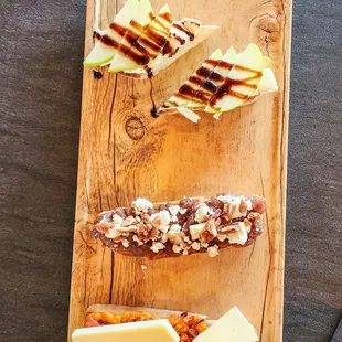 a wooden cutting board with cheese, crackers, and nuts