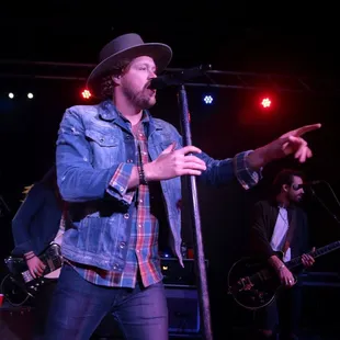a man in a fedora singing into a microphone