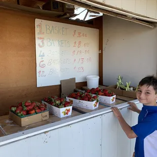 a boy standing in front of a fruit stand