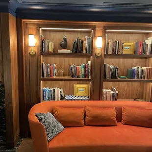 an orange couch in front of a bookshelf