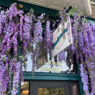 purple flowers hanging from the outside of the building