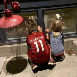 a boy and a girl looking in a window