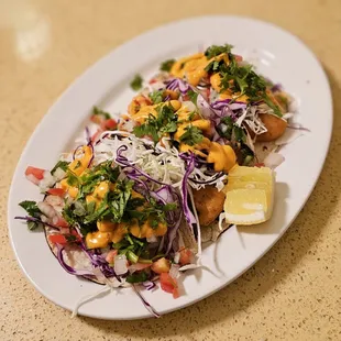 West Coast Tacos - crispy fillets on corn tortilas, topped w/ shredded cabbage, pico de gallo &amp; shriracha crema. Served with lemon wedge