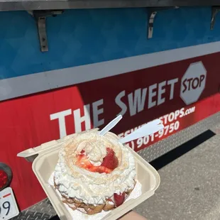 Funnel cake with powdered sugar, strawberries and ice cream.