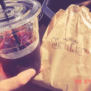 a person holding a drink and a bag