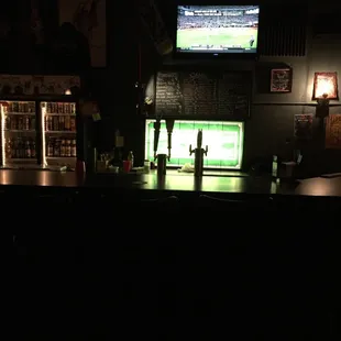 a dimly lit bar with a television in the background