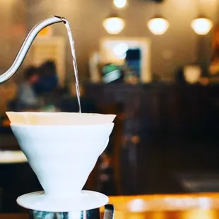 a coffee driper pouring water into a cup