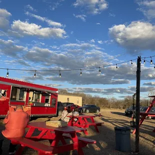 a woman sitting at a red picnic table