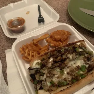 a sandwich and french fries in a styrofoam container