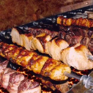 a variety of meats being cooked on a grill