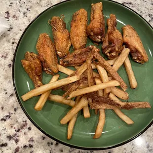 a plate of chicken wings and french fries