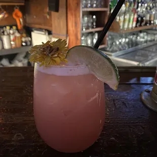 a pink drink with a lime garnish