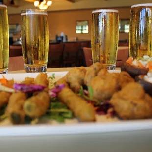 a plate of food and two glasses of beer