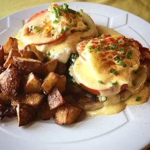a plate of eggs benedict with potatoes