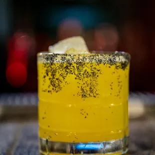 a yellow cocktail in a glass