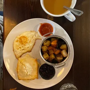 One egg over easy, biscuit, russet/sweet potato hash, homemade blueberry compote, and a cup of coffee made from beans roasted locally.