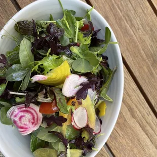 a bowl of salad on a wooden table