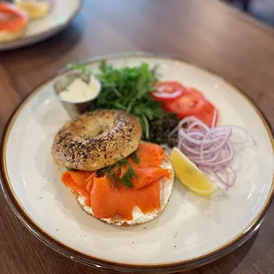 a bagel with salmon, onions, and tomatoes