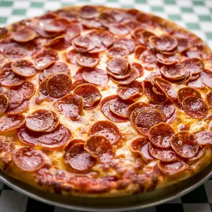 a pepperoni pizza on a checkered tablecloth