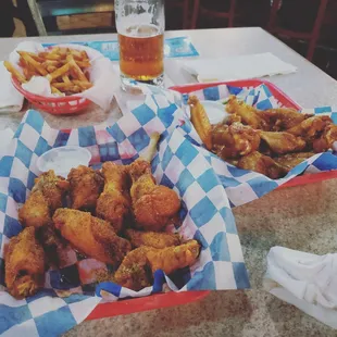 two baskets of chicken wings and a glass of beer