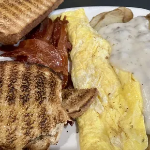 Eggs, fried potatoes, crispy bacon, dab of sausage gravy, and wheat toast