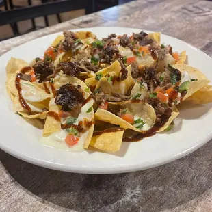 Our Famous Nachos. House fried tortilla chips  smothered with queso brisket, chicken or pulled pork. Topped with Pico de Gallo. Best Seller