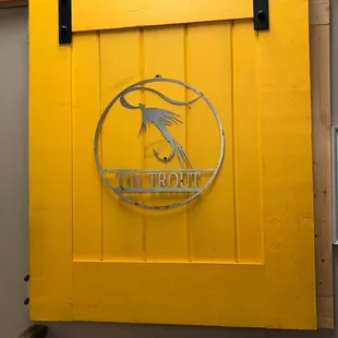 a yellow barn door with a metal bird on it