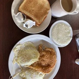 Pork chop breakfast with grits, eggs, &amp; toast.