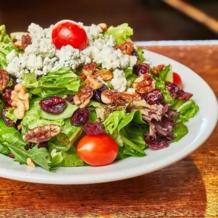 a plate of salad with cherry tomatoes and walnuts