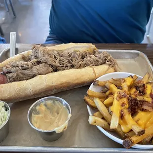 Large hotdog with pulled pork BBQ and loaded fries.