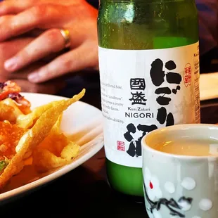 a plate of food and a bottle of sake