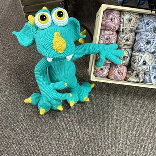 Crochet amigurumi monster posed to show off some sock yarns