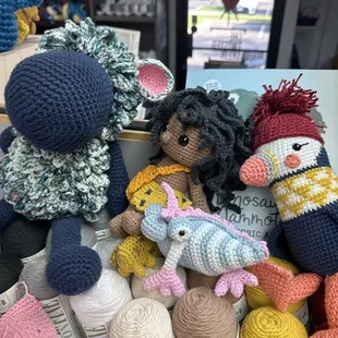 Photos of crochet Amigurumi sheep, caveman, three-eyed monster creature, and puffin on display in the shop