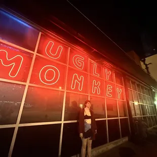 a woman standing in front of the neon sign