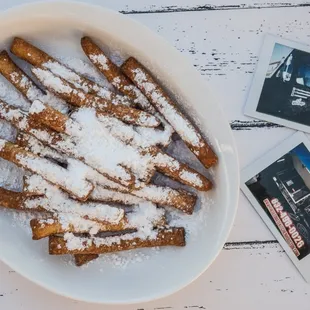 a bowl of french toast sticks with powdered sugar