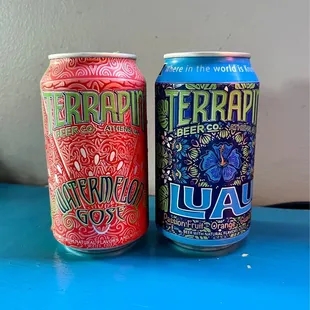 two cans of beer on a blue table