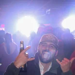 a man holding a beer and making a peace sign