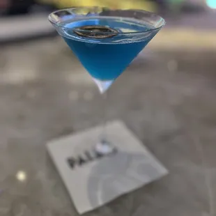 a blue cocktail in a martini glass