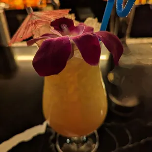 a cocktail with a purple flower in it