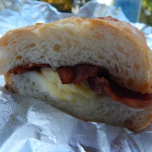 Half breakfast sandwich to-go with provolone, baguette bread, and bacon (came with egg).