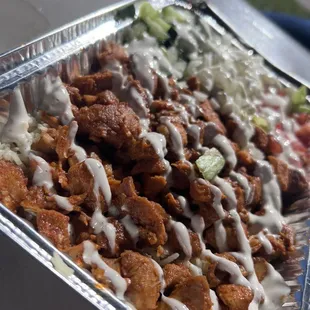 Chicken tikka over rice with salad and their signature sauces