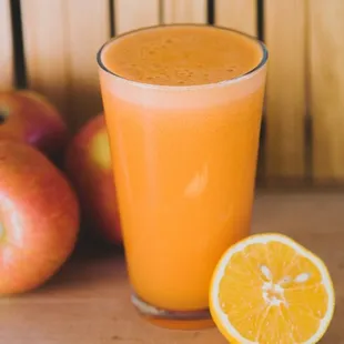 a glass of orange juice next to an orange slice