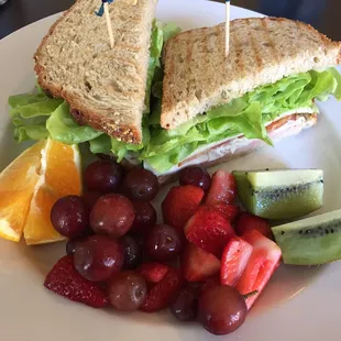 Club sandwich with a side of fruit.