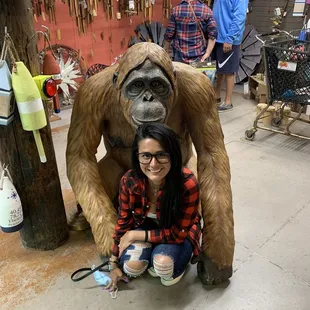 a woman sitting next to a statue of a gorilla