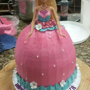 a barbie doll sitting on top of a cake