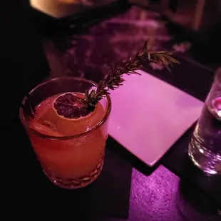 a drink with a sprig of rosemary