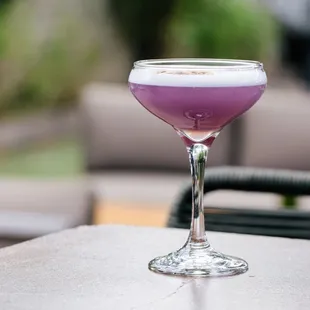 a purple drink in a glass on a table