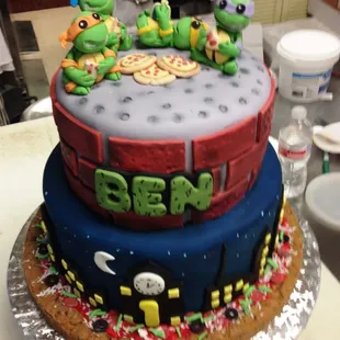 A two tiered fondant ocvered cake with gum paste details and characters.