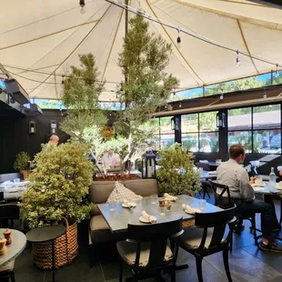 people sitting at tables under an umbrella